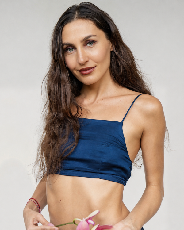 A woman modeling a navy blue silk two-piece set consisting of a Rui top and a Lin skirt, standing against a neutral light gray studio background.